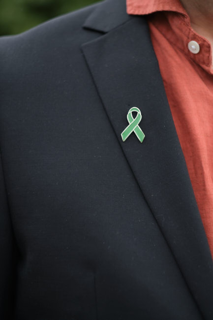 Green Ribbon237.RAF.p Närbild av en grön bandpin på en kavaj – symbol för engagemang i Green Ribbon-kampanjen för psykisk hälsa.